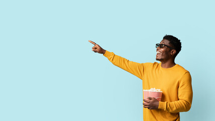 Emotional african american millennial guy in yellow cardigan with 3d glasses holding popcorn and...