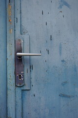 Retro door handle on old metal door with gray peeling paint