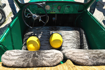 Interior of adapted car with hand controls and two yellow safety helmets on the furry front seat, special vehicle for drivers with limited leg mobility, concept of accessibility and road safety.