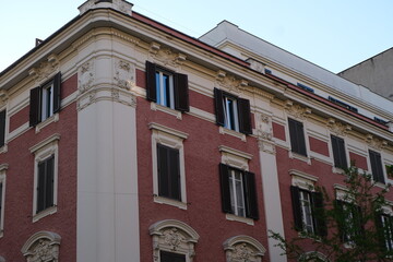 Naklejka premium Ornate building facade with symmetrical shuttered windows and textured pink stucco walls