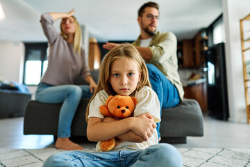 Portrait of a sad child, a little girl, while parents are having an argument at home