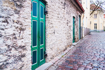 Textural minimalisme shapes an Old Town passage as stone walls, green wooden doors and winding cobblestones reveal everyday medieval character in winter silence. Tallinn, Estonia