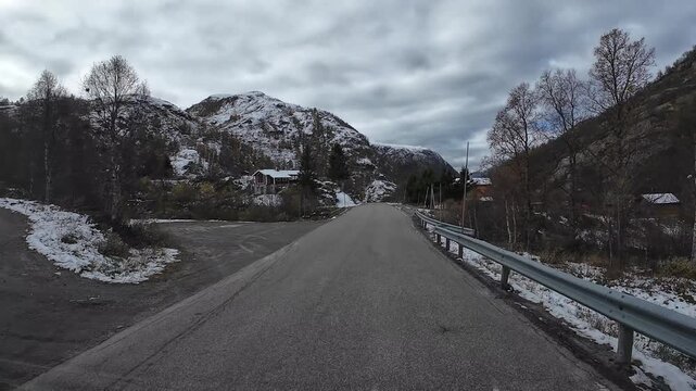 Point of view driving on a scenic mountain road with snow on a cloudy day in Sognefjellsvegen, Norway