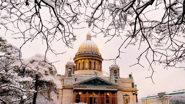 St. Petersburg, Russia - November 23, 2025: View of the snow-covered St. Isaac's Square with snow-covered trees and St. Isaac's Cathedral on a winter day at sunset. 4K