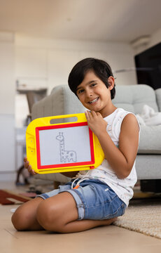 Child drawing on magnetic sketch pad with a smile