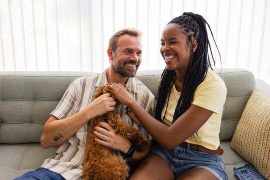 Multiethnic couple enjoying playful time with their pet dog indoors
