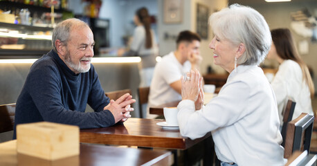 Fototapeta premium Couple elderly man and woman talking and drinking coffee in cafe