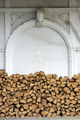 Stacked firewood in front of an antique decorative wall niche with stucco