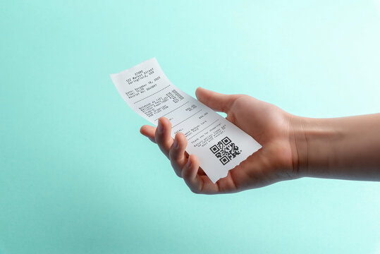 Hand holding paper receipt with qr code on blue background, digital payment and expense tracking concept for fintech apps, accounting software, and receipt management - Powered by Adobe