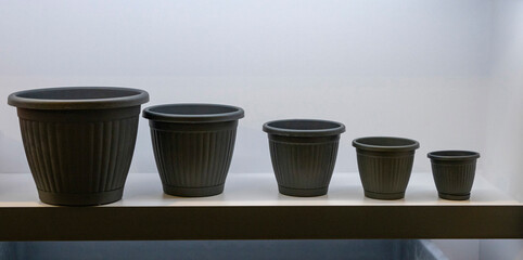 Plastic plant pot  patterns for sell in an shop.90mm  Plant Pot   herbs, seedlings, flowers.. Colorful plastic flower, plant, and seedling pots arranged in a specific order on the shelves. 