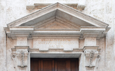 Naklejka premium Marble tympanum with Latin text on the lintel dedicated to Saint George and other martyrs on the San Giorgio church in Siena, Italy