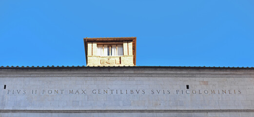 Naklejka premium Latin inscription on the Piccolomino Library next to the cathedral in Siena on a bright october day with blue sky in Tuscany, Italy