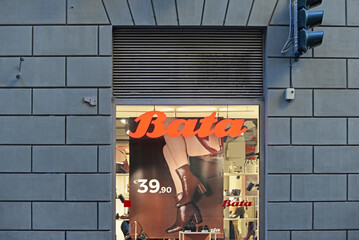 Naklejka premium SIENA, ITALY – OCTOBER 7, 2025: Bata shop window with orange logo and brown ankle boots for sale. The footwear and fashion accessories brand is headquartered in Lausanne, Switserland