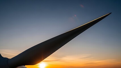 Low-angle view of a sleek wind turbine blade against a golden hour sky, representing renewable energy, sustainable technology, and an optimistic future