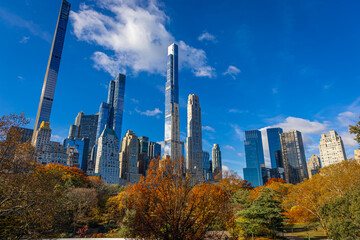 Fototapeta premium Central Park autumn path with Manhattan skyscrapers and blue sky above NYC