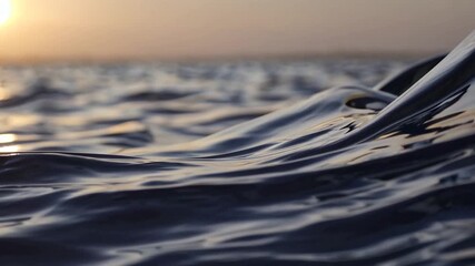 Gentle waves lap against each other as the golden sunlight glimmers across the surface of deep blue water. The tranquil scene invites reflection and evokes a sense of calm serenity