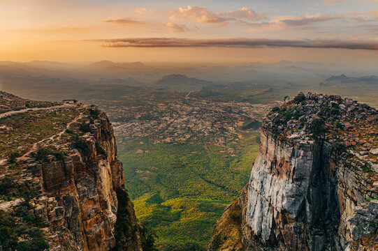 Aerial view of a dramatic escarpment and valley at sunset, with steep cliffs, vast plains, and distant mountains, overlooking the Tundavala Gap from Serra da Leba in Hu&iacute;la Province, Angola. 