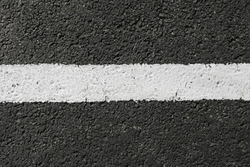 Fototapeta premium Asphalt road surface with white line. Street marking closeup texture. Black pavement background detail. Urban traffic lane pattern. Road safety symbol on asphalt. Empty copy space background.