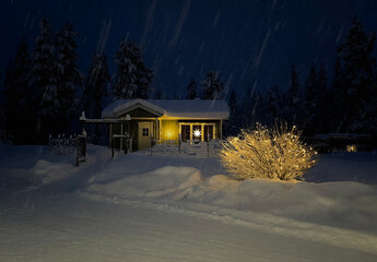 A small house decorated with Christmas lights on a snowy cold night
