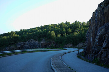 Curved road along rocky hillside in forest landscape