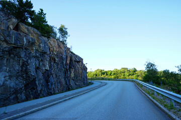 Curved road along rocky hillside in forest landscape