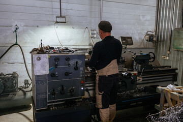 Turner working on lathe in workshop