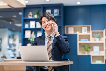 Fototapeta premium オフィスで電話する若いビジネスマン