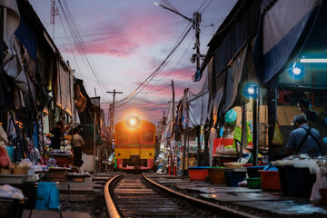 A train approaches the bustling Maeklong Railway Market as vendors prepare their colorful stalls....