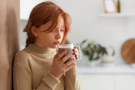 Teenage redhead girl drinking sweet cocoa in kitchen - Powered by Adobe