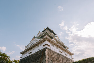 Fototapeta premium Dramatic Low Angle Architectural Detail of White Osaka Castle Tower Against a Cloudy Sky