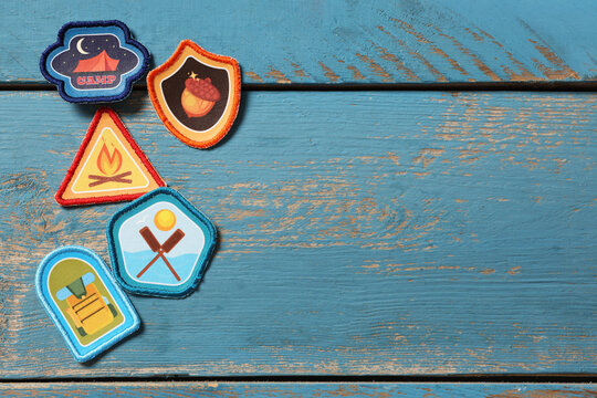 Different scout patches on blue wooden background