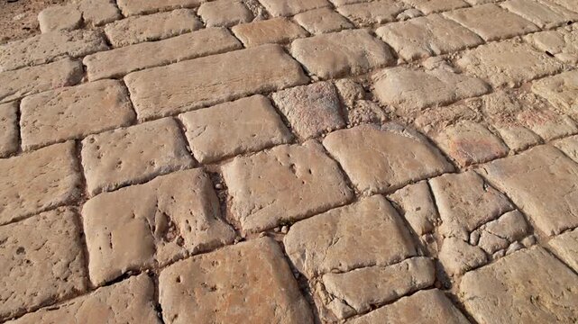Point of view walking on weathered limestone paving of an ancient Roman road at Zippori National Park in Galilee, Israel. Historic archaeology texture in warm light