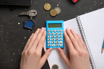 Female hands and calculator with notebook on dark background, closeup. Payment of utility bills...