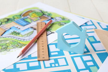 House figure with ruler, pencil and zoning plans on white wooden background, closeup
