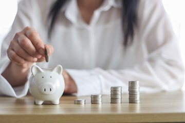women hand holding coin in to white piggy bank for use to business and money concept