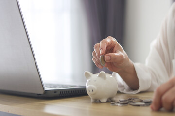 women hand holding coin in to white piggy bank for use to business and money concept