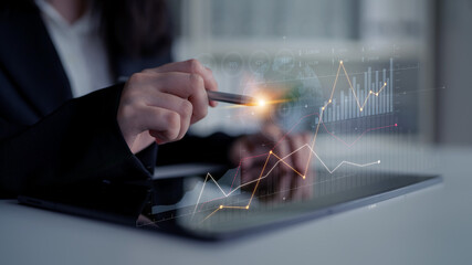 A business professional using a tablet to analyze financial data with graphs and charts,...