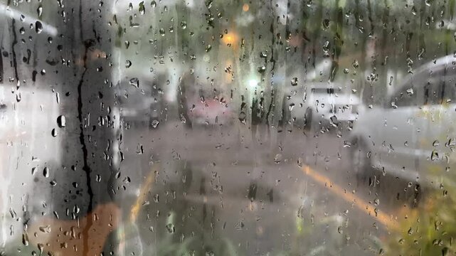 Blurred raindrops on glass window during raining. Melancholy Rain. rain sliding down slowly , rainstorm, rainy season. water. city. parking area. blur, blurry, bokeh. background. bubble, bubbles.