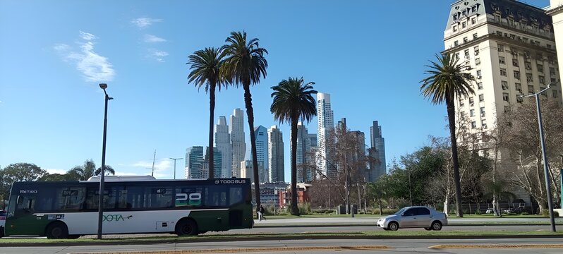 Modern city avenue with palm trees, bus and skyscrapers. Wide city avenue with palm trees, public transport bus and modern skyscrapers in the background under a clear blue sky. Urban landscape combini
