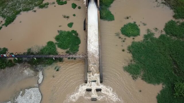 Aerial view of drainage channel while releasing water. Drainage channel is a natural or constructed watercourse or channel, having a definite bed and sides or banks, through which water flows.