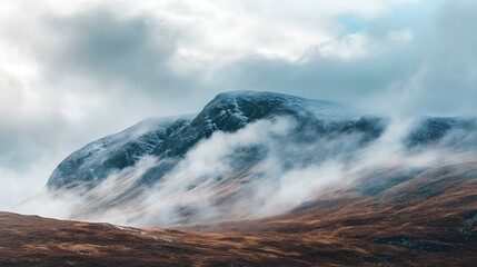 Snowy mountain peak shrouded in atmospheric fog and clouds