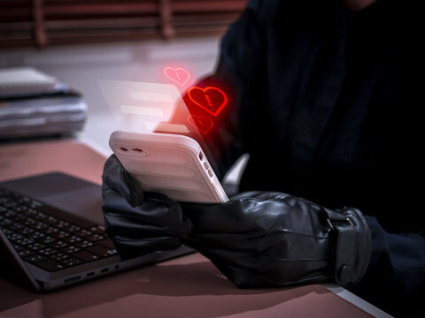 Romance scam concept showing a cybercriminal using a smartphone to deceive victims with fake love messages. Online dating fraud and social engineering risk through chat applications and social media.