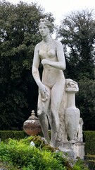 Rome, Italy - 12 January 2025. A moss-covered rock in a fountain holds a nude female statue with a jug, surrounded by statues, hedges, and trees in Villa Borghese Gardens.