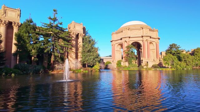 Classical Roman style rotunda and colonnades reflected in the calm lagoon during a vibrant golden sunrise in San Francisco