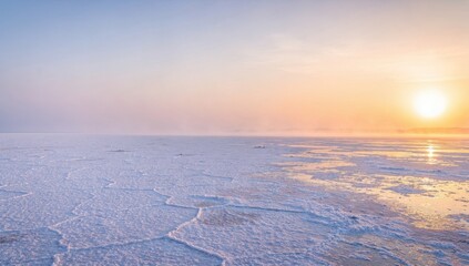 Vast salt flats landscape at sunrise with a bright sun reflecting in the water and a colorful sky with hues of pink, orange, and blue.