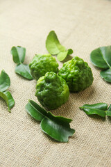 Kaffir lime or bergamot fruit, kaffir lime or citrus hystrix fruit in a bowl, decorated with kaffir lime leaves around it and placed on a base made of burlap