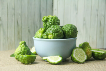 Kaffir lime or bergamot fruit, kaffir lime or citrus hystrix fruit in a bowl, decorated with kaffir lime leaves around it and placed on a base made of burlap