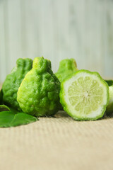 Citrus hystrix or kaffir lime or bergamot sliced fruit and its leaves isolated on a brown burlap base