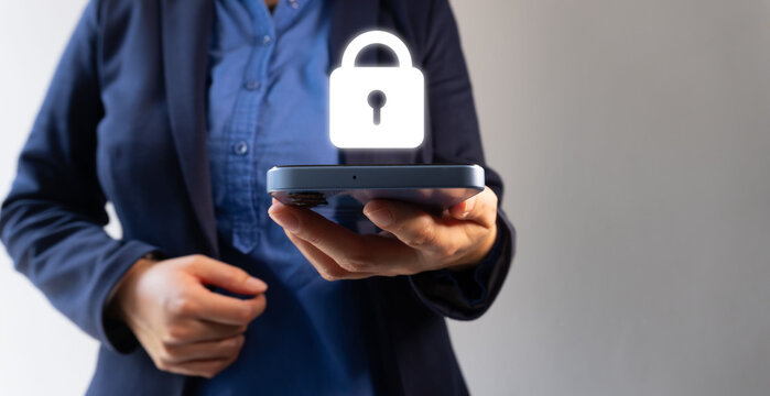A businesswoman holds a cell phone with a glowing padlock symbol, representing digital security and data protection in corporate mobile device use. - Powered by Adobe