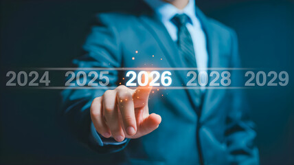 Obraz premium Businessman's hand touching the year 2026 on a futuristic timeline, symbolizing future planning and goals